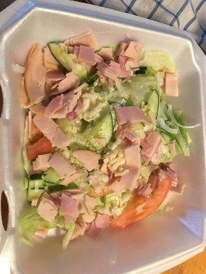 Iceberg lettuce 1 slice tomato 1 slice cucumber 2 slice ham shredded plate half full this is Greg's chef salad , need be called Ripoff salad