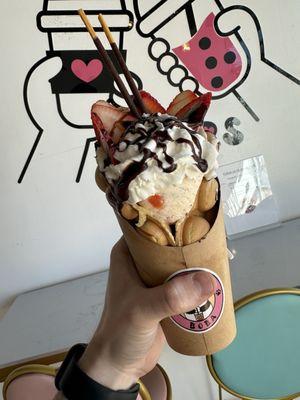 Chocolate chip waffle with banana split ice cream, strawberry toppings, and chocolate syrup.