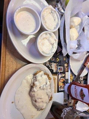 Country fried chicken with two sides of mashed potatoes and gravy and an extra gravy