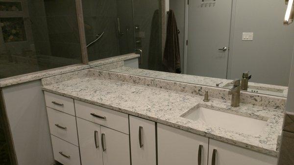 White frameless vainty with quartz top and square sink.