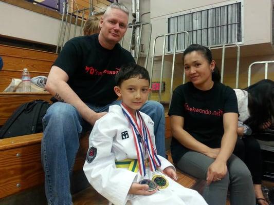 Trey showing off all his medals at the UTA tournament with Mom and Dad