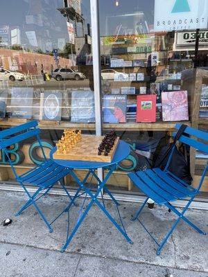 Folding wooden chess board on the sidewalk outside of the bookstore.