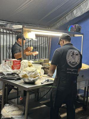 One cook making hand made tortillas the other the tacos.