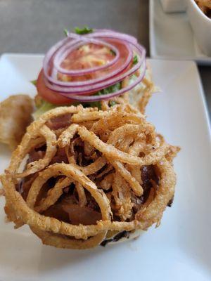 Onion straws on a juicy burger.