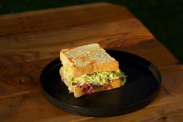 Our Pastrami Mami comes with hot sliced pastrami, mustard and mayo and sweet honey slaw  and pickles!