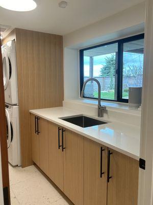 Beautiful new custom cabinets in the laundry room with new sink and faucet, as well as black vinyl windows and new stackable washer/dryer.