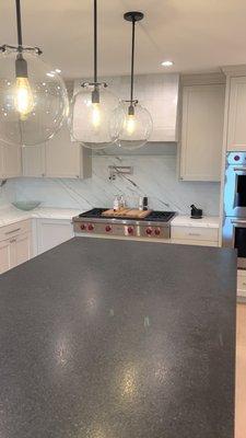 Black brushed granite island with Calacatta marble counter and backsplash and Zellij  Gloss Oyster tile on the hood.