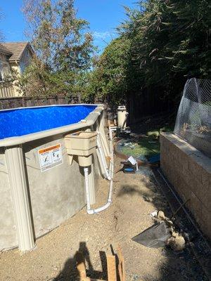 Side of pool with skimmer, pump and pipes