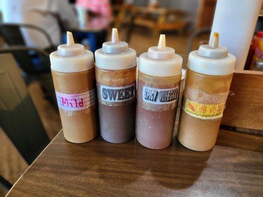 Four sauces (mild, sweet, spicy vinegar, & hot) on each individual table.