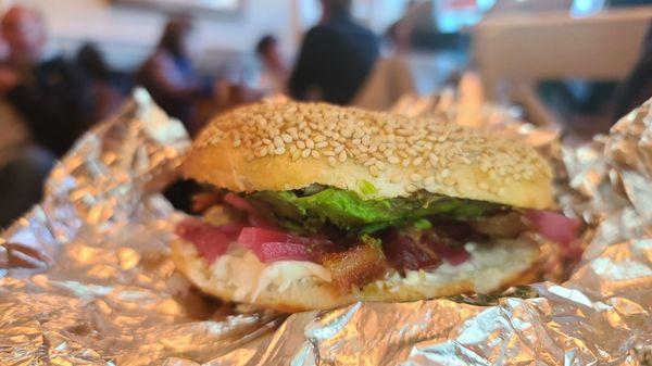 Bacon, avocado, pickled red onion on a sesame bagel.