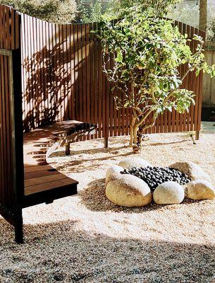 Ipe wood curved bench and divider screen, gravel and rock fire pit