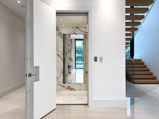 Custom elevator design with mirror and marble walls to match the home's interior.