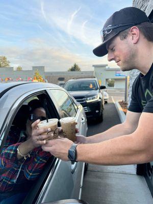 Gravista handing 2 drinks to a customer in our drive thru