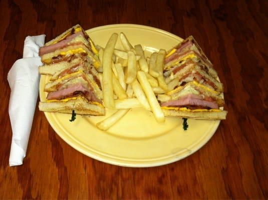 This is our amazing club sandwich. Made with ham, bacon, cheese, lettuce, tomatoes, & mayonnaise. Served with French fries.