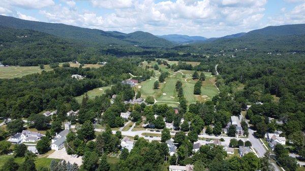 Drone photo of town of Dorset with lush trees, rolling green mountains and green grass