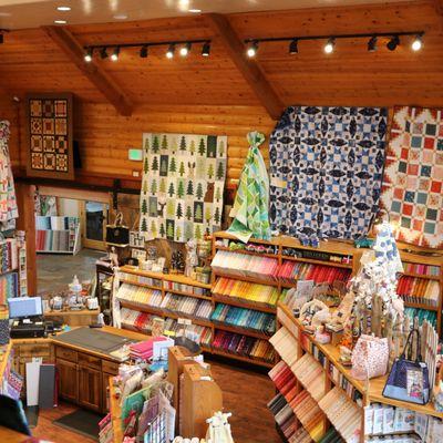 More quilts on display hanging above the shelves of colorful fabric.