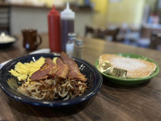 two eggs scrambled soft, bacon, hash browns, and pancakes.