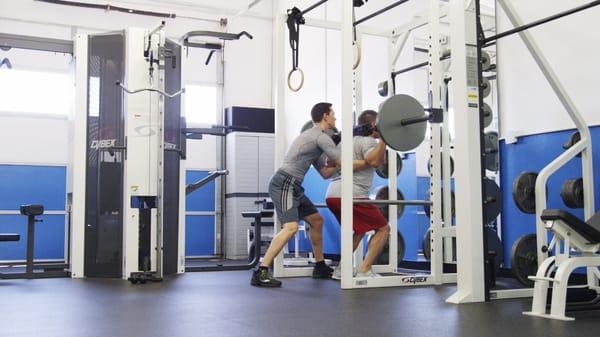 Personal Trainer George spots client David during squats.