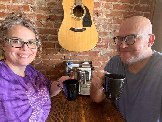 Two people seated and drinking coffee.