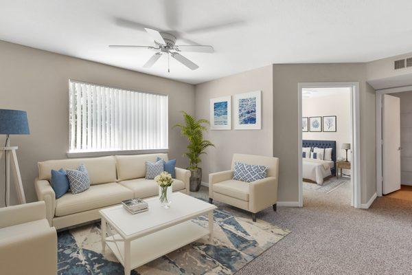 Staged living room with carpet flooring, multi speed ceiling fan, and large window