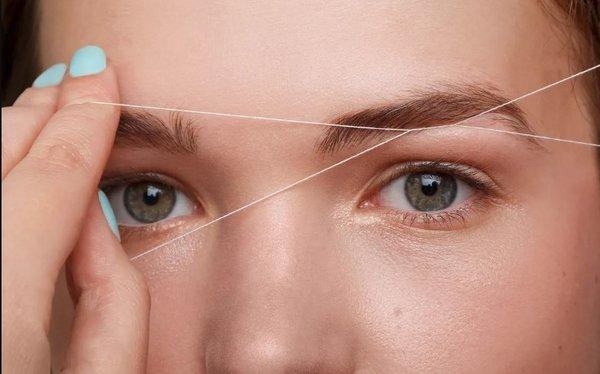 Eyebrow threading : A precise hair removal technique using a twisted cotton thread to shape and define eyebrows.