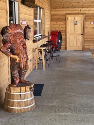 Outdoor seating w/ a crazy wooden statue.