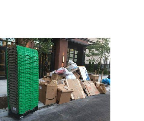 A neat stack of reusable BoxUp moving bins next to a heap of cardboard and filler material.