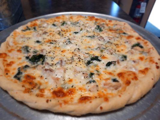 Chicken alfredo pizza with creamy alfredo sauce, spinach, and shredded chicken, on our standard thin crust