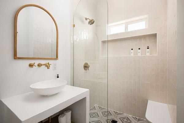 Hall bath designed by our sellers with modern touches including custom arched shower doors and custom cement vanity.