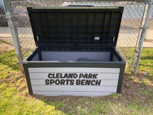 There is a sports bench with soccer balls, baseballs, mits, yoga mats and other fun sports equipment.