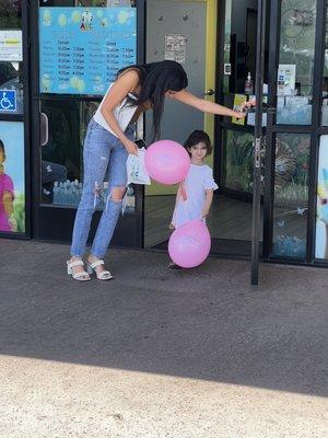 Ella's little sister walking out of the clinic with a pink ballon.