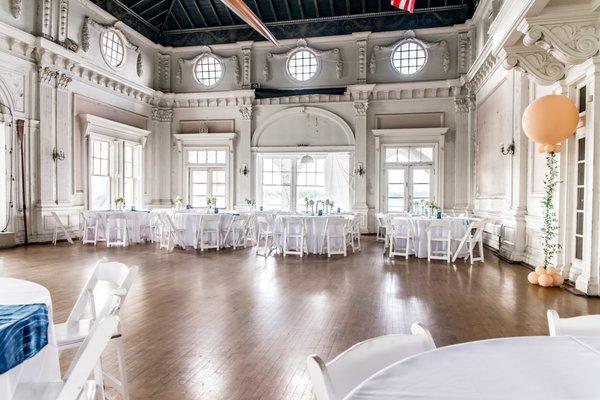 The historic ballroom prepped for a summer wedding with white linen & a flood of natural light