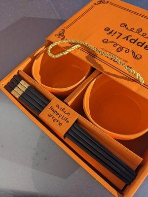 Gift box open and showing two small orange bowls and a set of chopsticks.