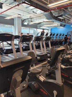 Close up on cardio equipment on the other side of the gym.