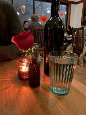 Table setting with rose, candle, and water glasses.