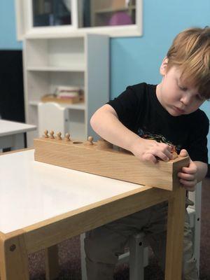 Child practicing Montessori cylinders to improve hand and eye coordination.