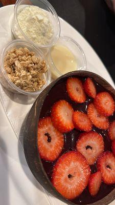 Açaí bowl topped with strawberries -- sweet powdered milk, condensed milk, and granola condiments.