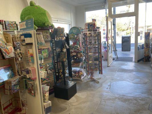 Right side interior of the store, has coloring books, blind bags, and stuffed animals.