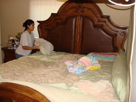 An experienced cleaner making a bed