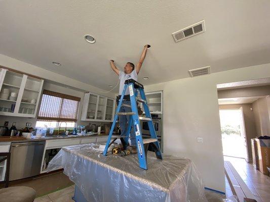 Jesus Jaime installing kitchen island chandeliers.