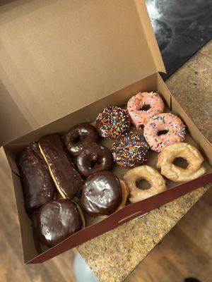 Custom dozen donuts with Boston cream, chocolate bars, double trouble, chocolate and strawberry frosted sprinkle cake, and Old Fashioned.