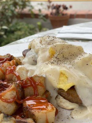 Biscuits and gravy with sausage and home fries.