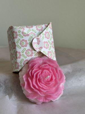 Pink candle in the shape of a rose in a festive box.