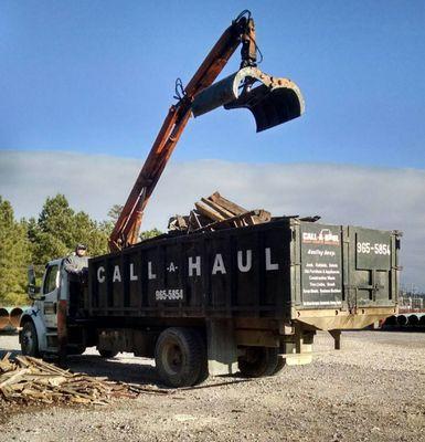 Loading heavy junk items by grapple crane.