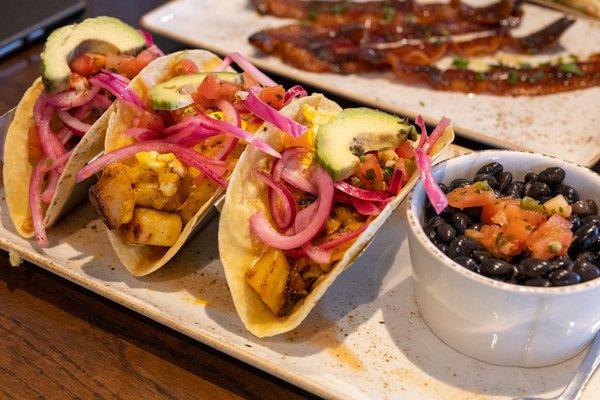 CAULI-RIZO BREAKFAST TACOS. Cheddar and Monterey Jack, potatoes, avocado, lime crema, house-pickled red onions and cilantro