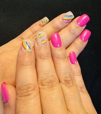 Two different shades of pink color on natural nails with stickers and gems added.