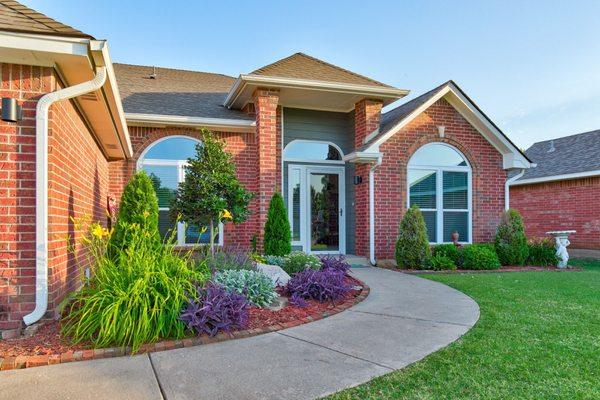 Front facing exterior photo of a Norman OK home with a colorful garden.