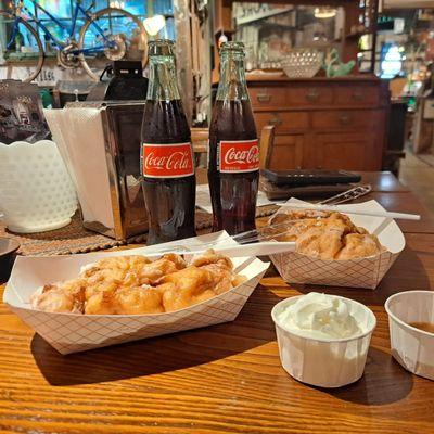 Peach fritters with caramel and whipped topping on the side. Coca-Cola from a glass bottle to top it off!