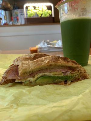 Egg, cheese, and ham croissant with added avocado and a large green juice