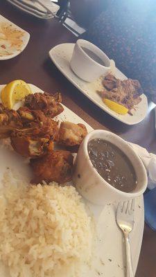 Chicharron de pollo white rice and black beans in the front and pernil white rice and black beans